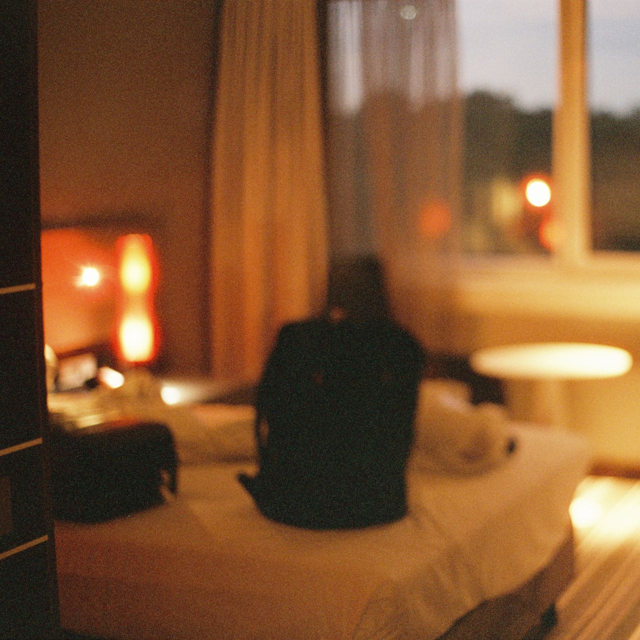 blurry photo of an empty hotel room with a backpack on a bed